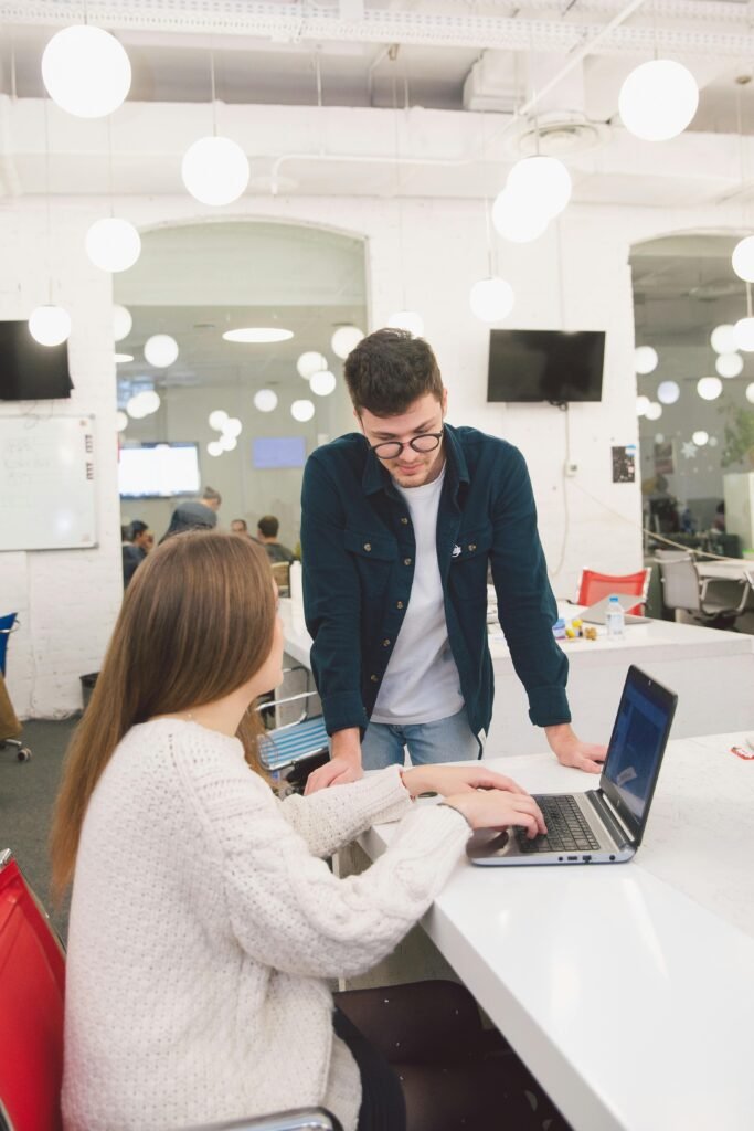 Two colleagues engaged in a discussion over a laptop in a bright, contemporary office space.